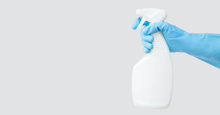 掃除用スプレーを持つゴム手袋をはめた手